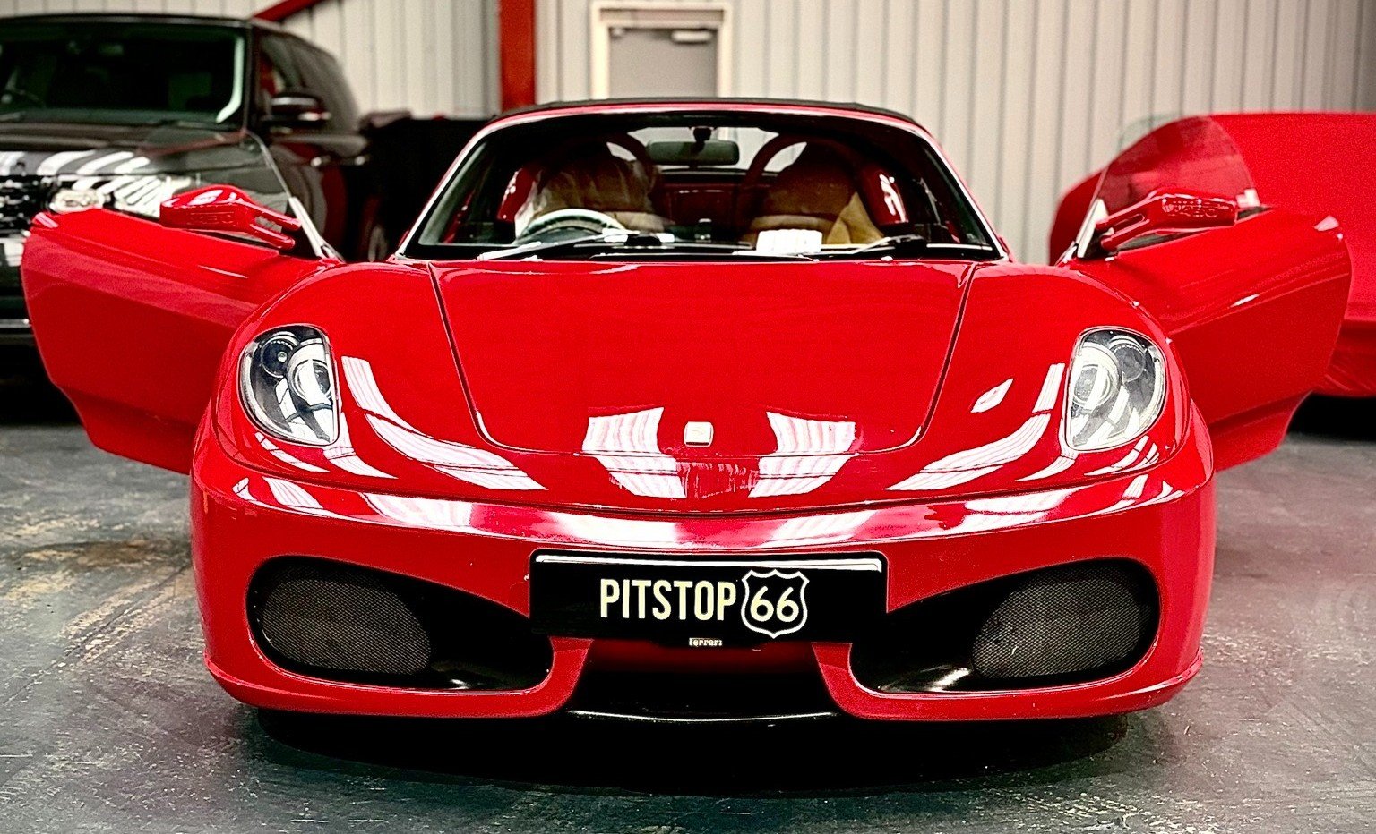 View along a row of cars stored indoors at Pitstop 66, with the Pitstop 66 logo on the wall