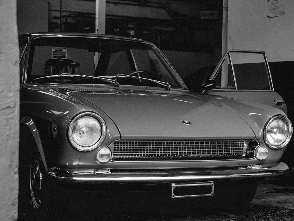 Classic coupe with its driver door open inside a dim lock-up garage