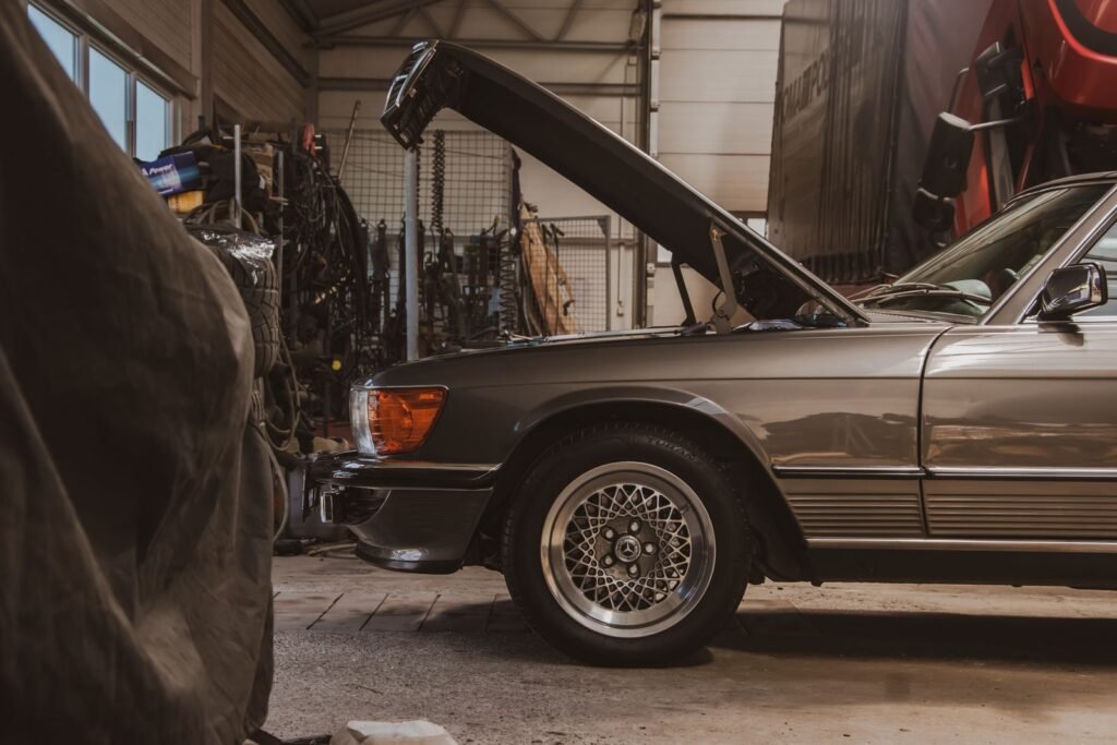 Classic Mercedes with its bonnet up being prepared for storage in a garage